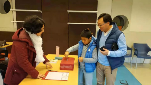 家长与孩子一起在学校捐赠（中国华文教育基金会 供图）